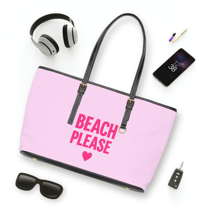 Pink tote bag with 'Beach Please' text and heart symbol, surrounded by accessories on a white background